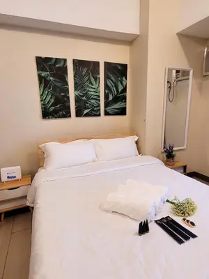 a bedroom with a white bed with three pictures on the wall at Urban Studio with Balcony in Manila