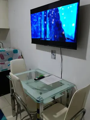 a glass table with chairs and a television on a wall at Sea residences Sweetest escape in Manila