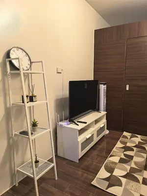 a living room with a tv and a shelf at Pine3s Turf in Manila