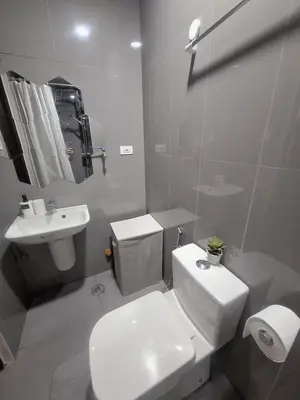 a white bathroom with a toilet and a sink at Pine3s Turf in Manila