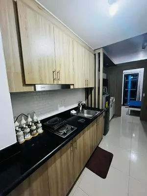 a kitchen with wooden cabinets and a sink in it at EM's Staycation Walking distance to Mall of Asia in Manila
