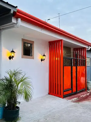 a red door on a white building with a plant at PPL Homestay