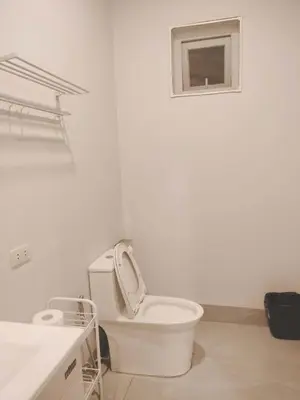 a white bathroom with a toilet and a window at Pleasant Hill Cabins near Tagaytay Highlands
