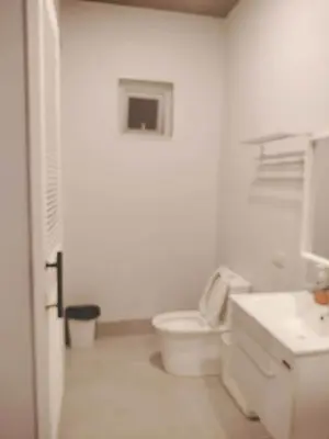 a white bathroom with a toilet and a sink at Pleasant Hill Cabins near Tagaytay Highlands