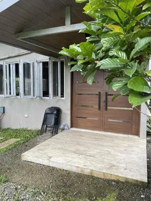 a wooden garage door with a chair in front of a house at Pleasant Hill Cabins near Tagaytay Highlands