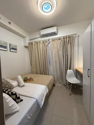 a bedroom with two beds and a chair in it at The Lumora Cove at Shore 2 Residences in Manila