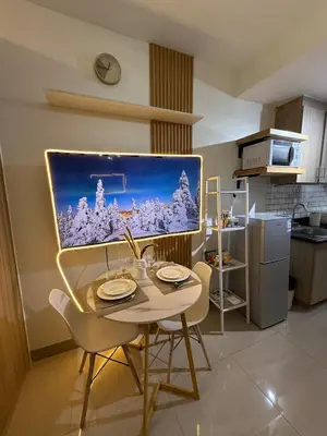 a dining room with a table and a tv on the wall at The Lumora Cove at Shore 2 Residences in Manila