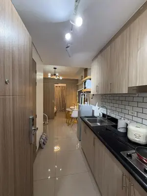 a kitchen with wooden cabinets and a counter top at The Lumora Cove at Shore 2 Residences in Manila