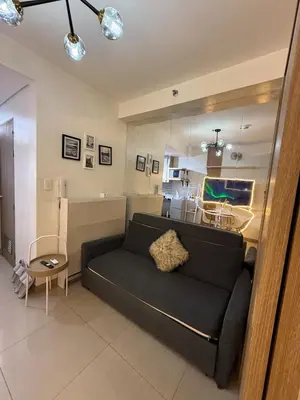 a living room with a black couch and a table at The Lumora Cove at Shore 2 Residences in Manila