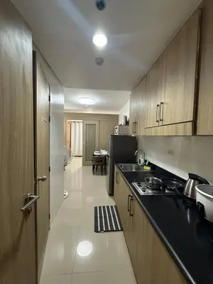 a kitchen with wooden cabinets and a black counter top at The Grand Haven at Shore Residences in Manila