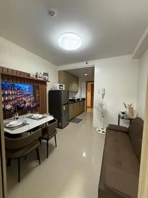a living room with a couch and a table and a kitchen at The Grand Haven at Shore Residences in Manila