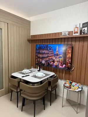 a dining room with a table and a tv on a wall at The Grand Haven at Shore Residences in Manila