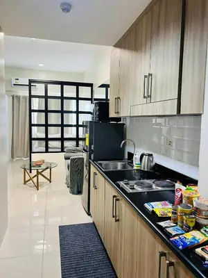 a kitchen with wooden cabinets and a black counter top at The Sunset Cozy Suite at Shore 1 in Manila
