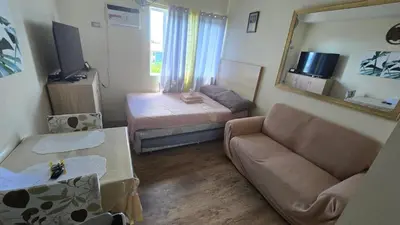 a living room with a couch and a bed and a mirror at The Cozy Place in Silang