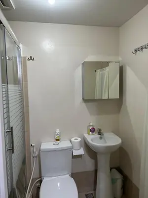 a white bathroom with a toilet and a sink at The Cozy Place in Silang