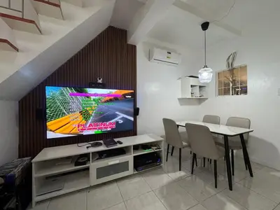 a dining room with a table and a television on a wall at Modern 2 Storey 2BR Home with 2 Parking Space in Manila