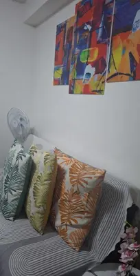 a pile of pillows on a bed with a painting at Chen Staycation at Shore in Manila