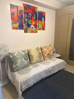 a couch in a living room with paintings on the wall at Chen Staycation at Shore in Manila