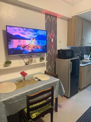 a kitchen with a table and a television on a wall at Chen Staycation at Shore in Manila