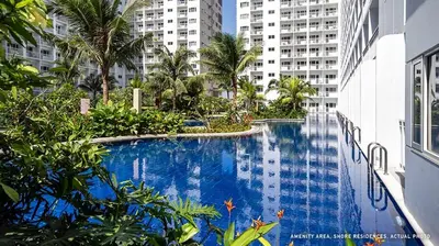 a large swimming pool with palm trees and buildings at Japandi Aesthetic Corner Unit, Calm & Private, MOA in Manila