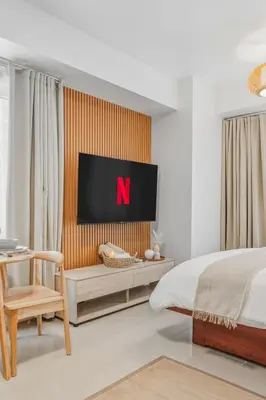 a bedroom with a bed and a tv on a wall at Japandi Aesthetic Corner Unit, Calm & Private, MOA in Manila