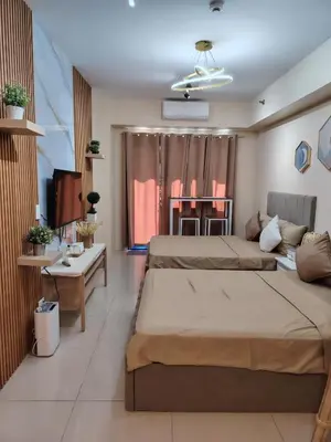 a hotel room with two beds and a table at Ana's Homestay at Sea Residences in Manila