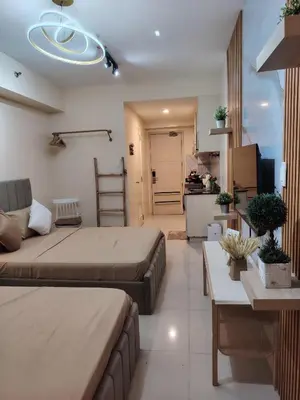 a bedroom with two beds and a living room at Ana's Homestay at Sea Residences in Manila