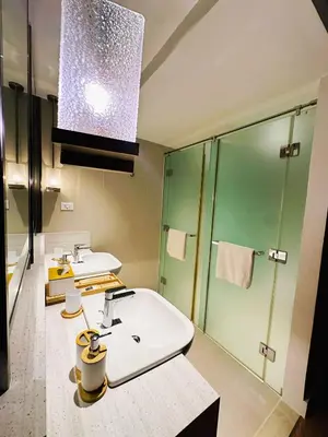 a bathroom with two sinks and a shower at DE LUX SUITE at Novotel Manila Hotel Residences Acqua in Manila