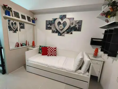 a small room with a white bed with hearts on the wall at Lornas Place in Manila