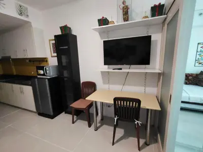 a kitchen with a table and two chairs and a tv at Lornas Place in Manila