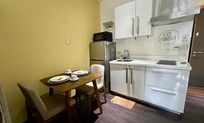 a small kitchen with a table and a refrigerator at Cozy Studio Unit at The Knightsbridge Residences in Manila