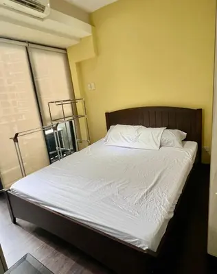 a bed with white sheets and pillows in a room at Cozy Studio Unit at The Knightsbridge Residences in Manila