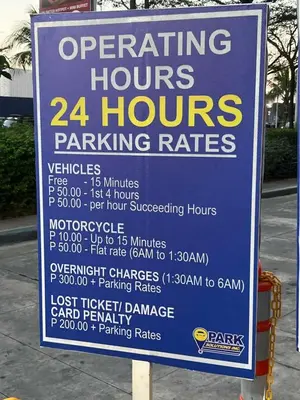 a sign for a parking hours and parking rates at Pit Stop Haven Near Manila Airport and Mall of Asia in Manila