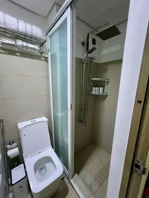 a bathroom with a toilet and a glass shower at Pit Stop Haven Near Manila Airport and Mall of Asia in Manila