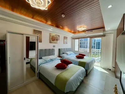 a bedroom with two beds with red pillows at Pit Stop Haven Near Manila Airport and Mall of Asia in Manila