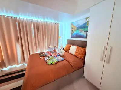 a bedroom with a bed with orange sheets and a window at Casa Maria urban resort in Manila