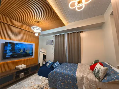 a bedroom with a bed and a flat screen tv at The Verdin Sweet at Maple Grove Gen Tri Cavite in General Trias