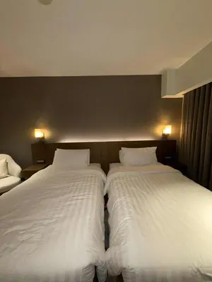 two beds in a hotel room with white sheets at Novotel at Acqua, The Hotel Residences by RM in Manila