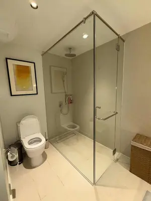 a bathroom with a toilet and a glass shower stall at Novotel at Acqua, The Hotel Residences by RM in Manila
