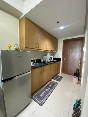 a kitchen with a stainless steel refrigerator and wooden cabinets at Maggielyn Jacob Place in Manila