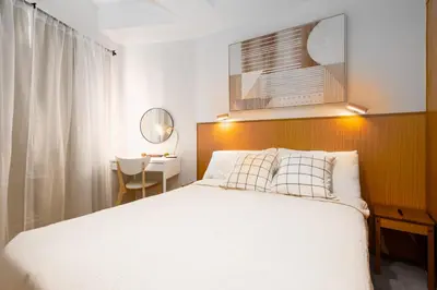 a bedroom with a large white bed and a desk at Brand New Japandi - Modern 1 BR Walk to MOA in Manila