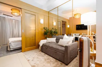 a living room with a couch and a bedroom at Brand New Japandi - Modern 1 BR Walk to MOA in Manila
