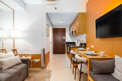 a kitchen and living room with a couch and a table at Brand New Japandi - Modern 1 BR Walk to MOA in Manila