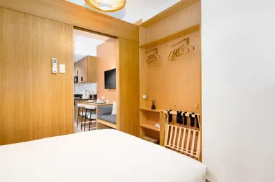 a bedroom with a bed and a living room at Brand New Japandi - Modern 1 BR Walk to MOA in Manila