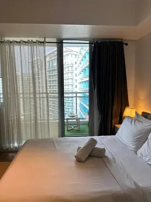a bedroom with a white bed with a large window at Condo near airport - azure residences in Manila