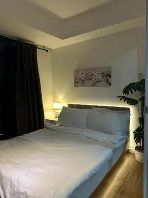 a bedroom with a bed with white sheets and a plant at Condo near airport - azure residences in Manila