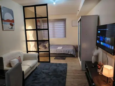 a living room with a couch and a bed and a mirror at NestAway Condo in Manila