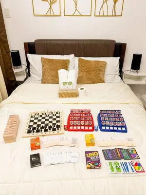 a bed with a display of board games on it at Azure 1BR Near NAIA 20 mins Wave Pool in Manila