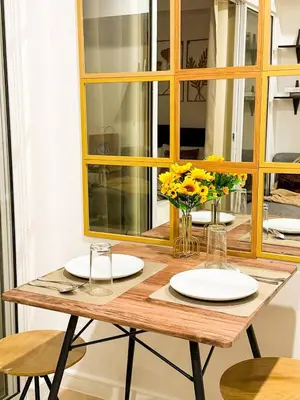 a wooden table with plates and yellow flowers on it at Azure 1BR Near NAIA 20 mins Wave Pool in Manila