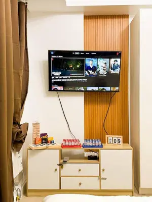 a flat screen tv on a wall above a dresser at Azure 1BR Near NAIA 20 mins Wave Pool in Manila